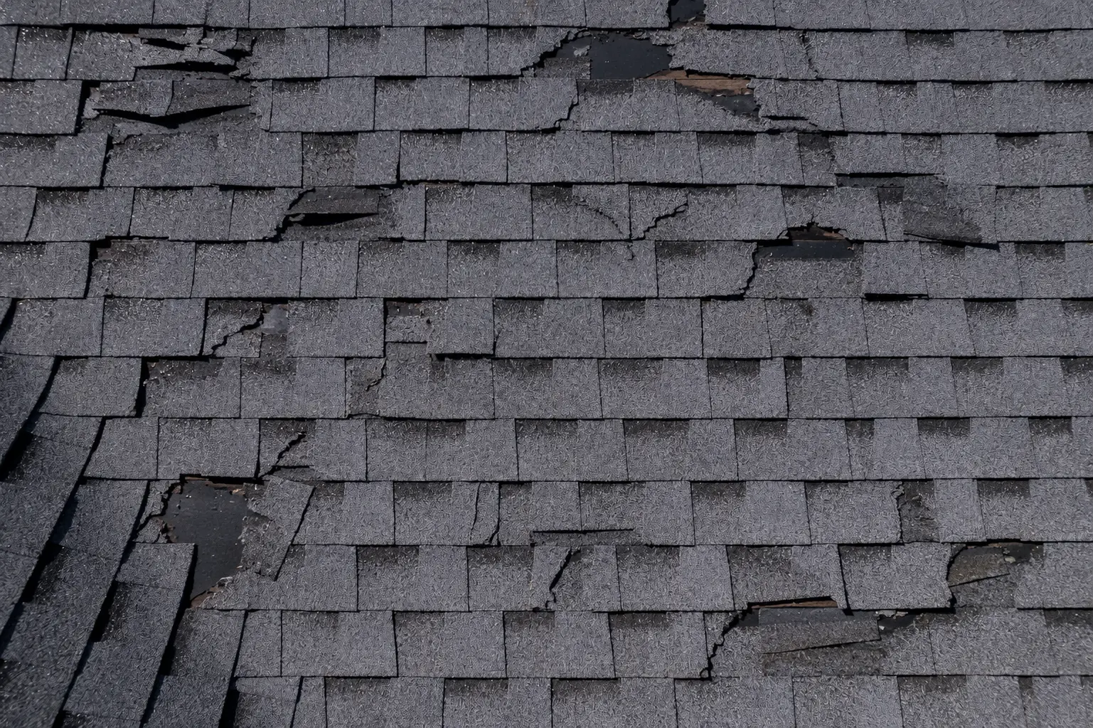 Aged, storm-damaged shingle roof before replacement